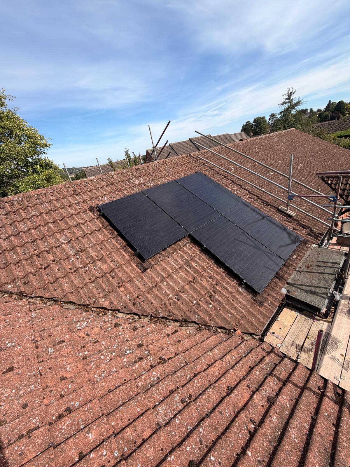 Four solar panels with bird protection mesh on a red tiled roof